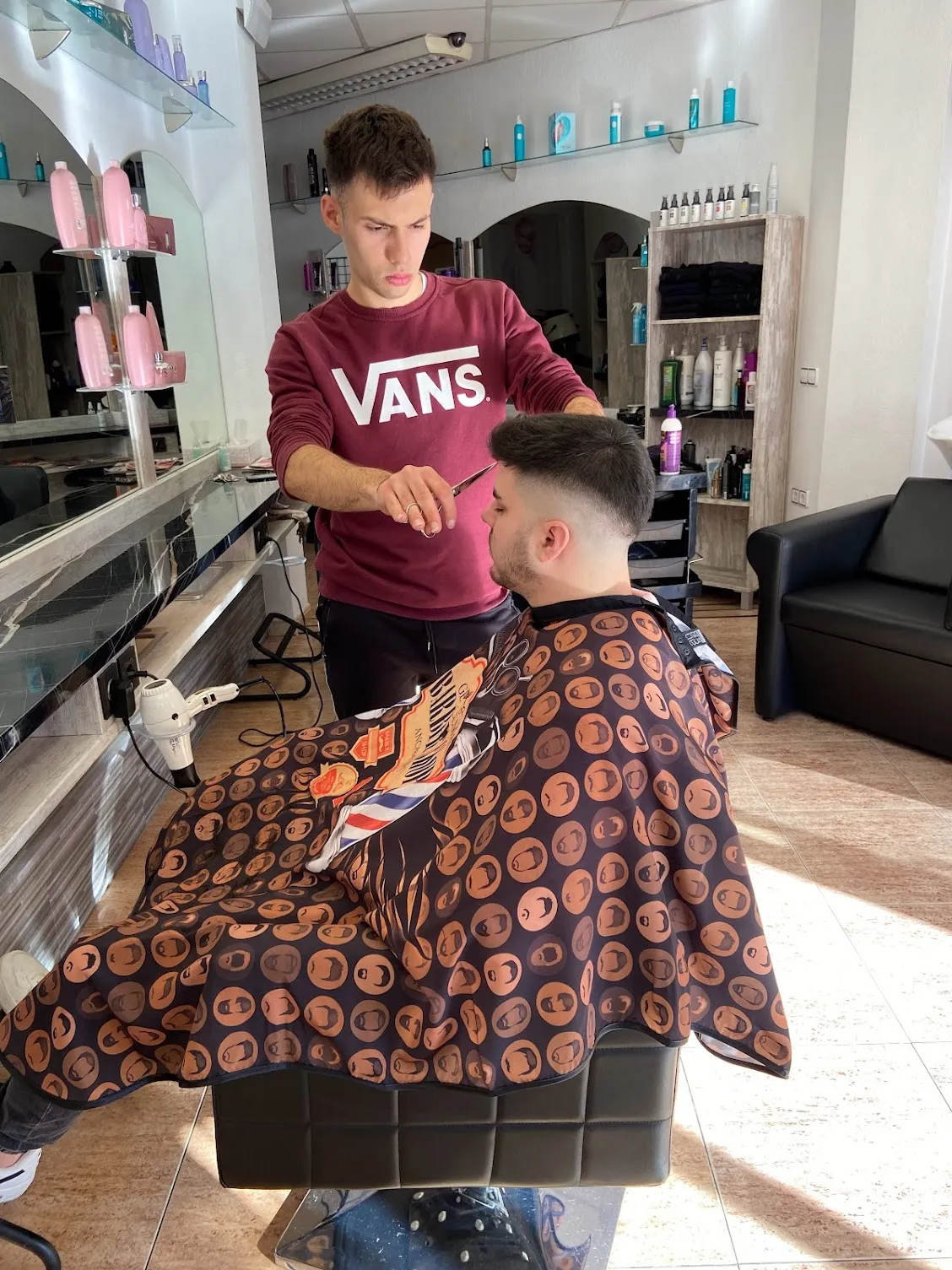 Barbero de Perruqueria Angela cortando el pelo a un cliente en el salón